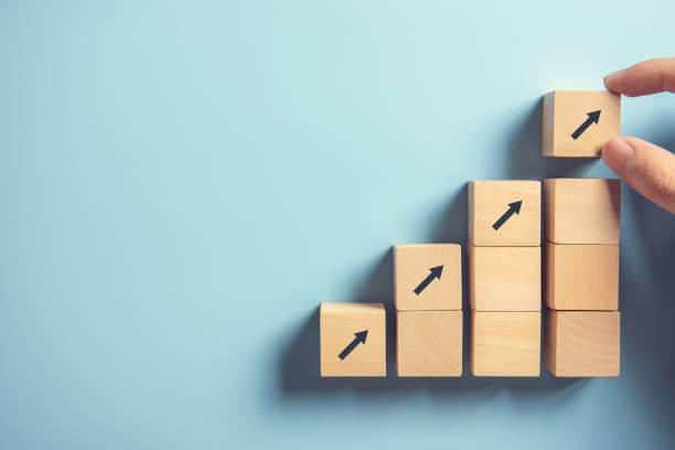 Close up man hand arranging wood block stacking as step stair on paper pink background. Business concept growth success process, copy space.