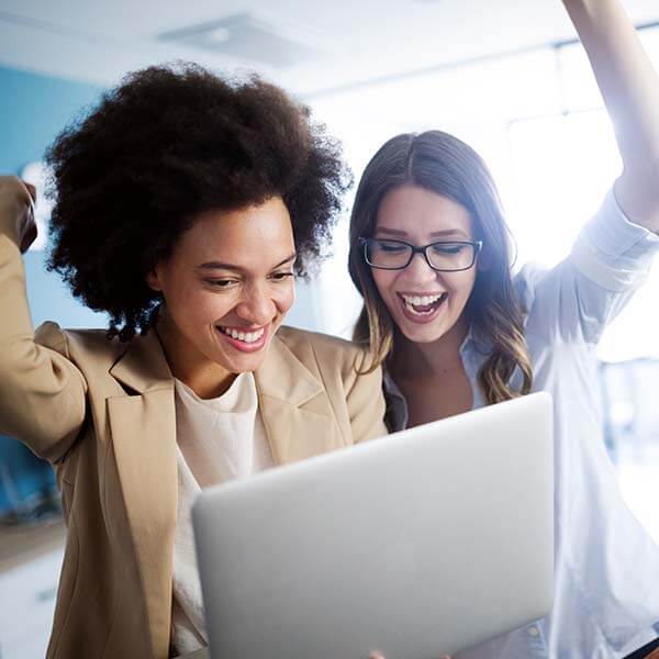 Two women cheering looking at computer