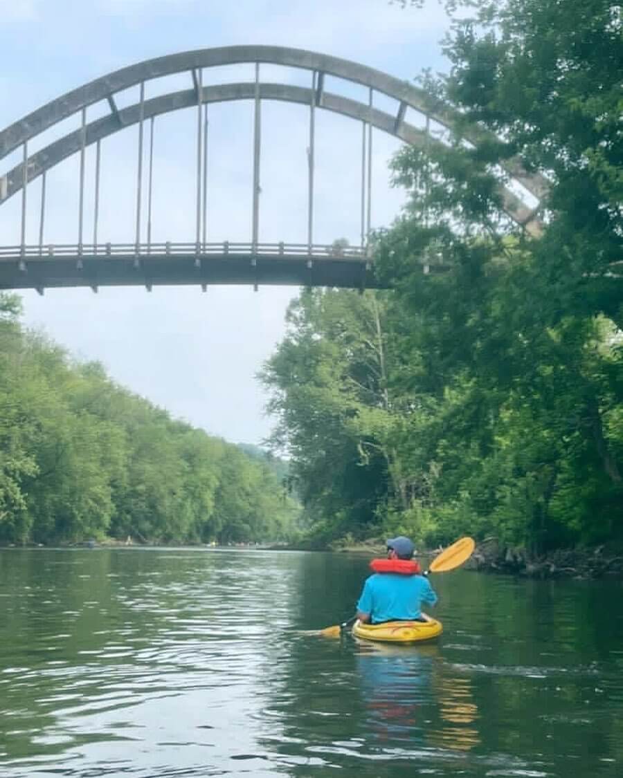 person kayaking near bridge