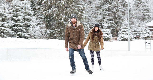 young man and woman skating outside with snowy backdrop