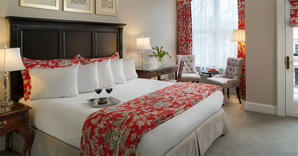 luxurious hotel room with wine glasses on the bed and fresh flowers