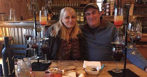 woman and man sitting at table with wine glasses and cheese plate