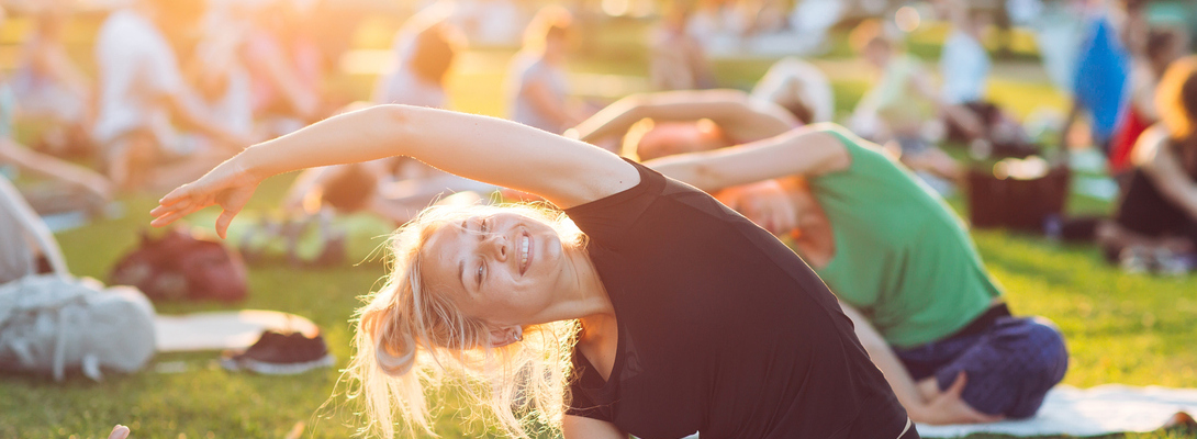 A group of young people do yoga in the Park at sunset.