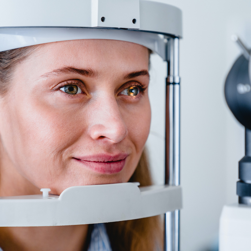 Cropped photo of cheerful smiling patient checking her vision with the help of ophthalmic tools