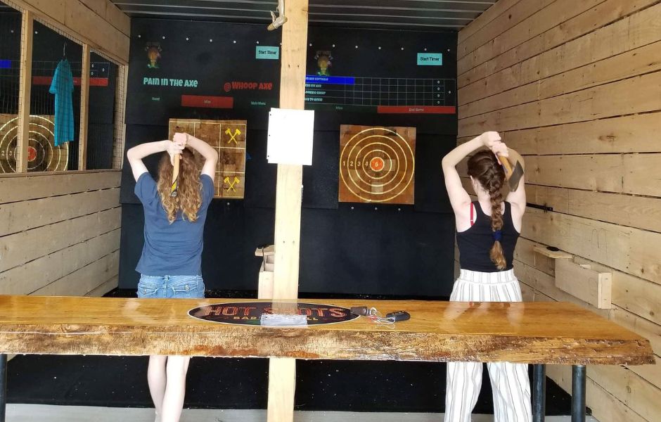 Two girls participating in axe throwing