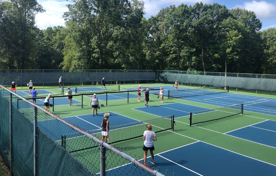 Players on multiple blue pickleball courts