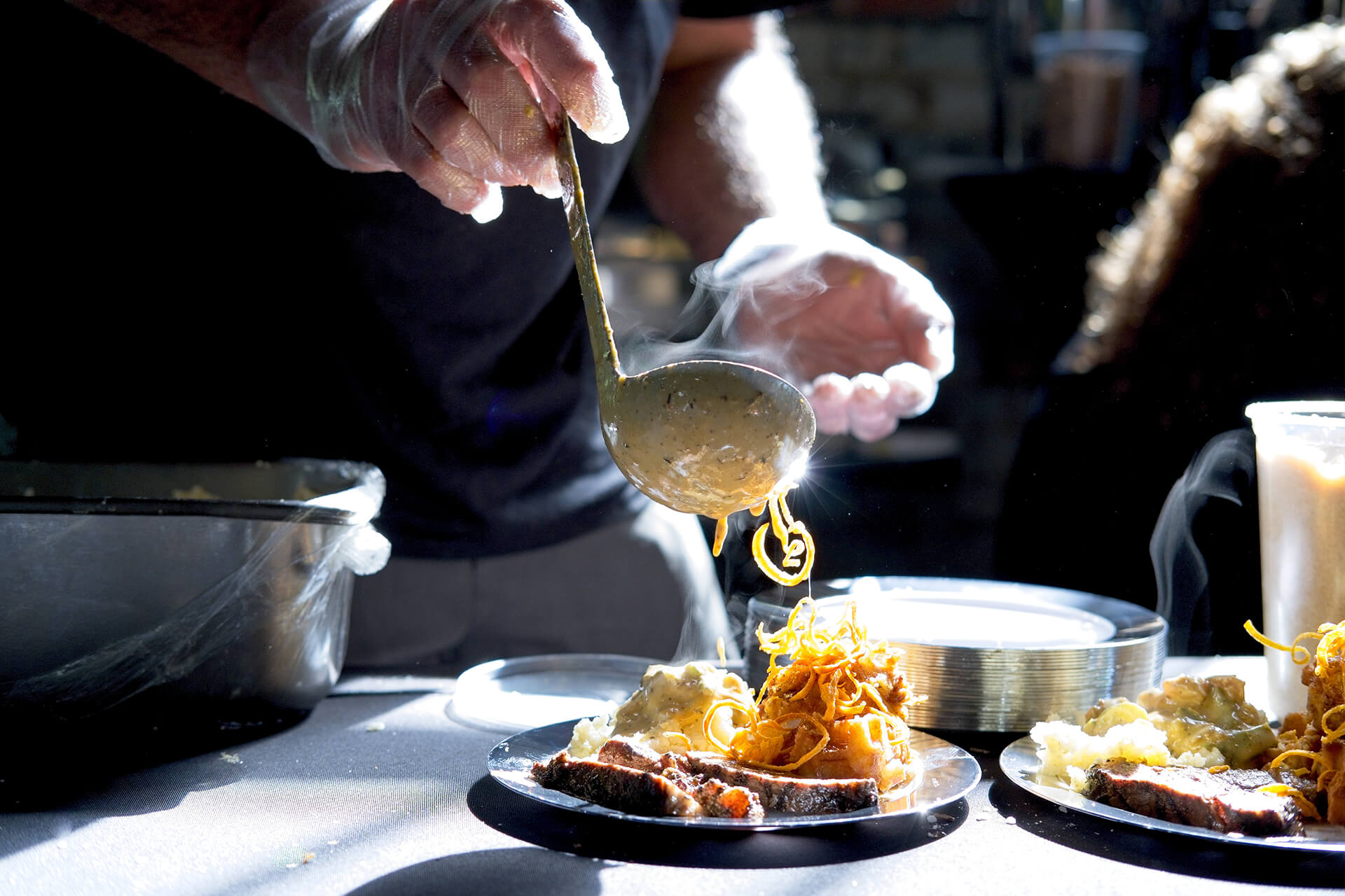 Cody Allen of Legends, Steakhouse in Murphy, NC, pours the finishing touches on a signature dish at the 2022 Forks and Corks event held June 2, at the historic Hackney Warehouse.