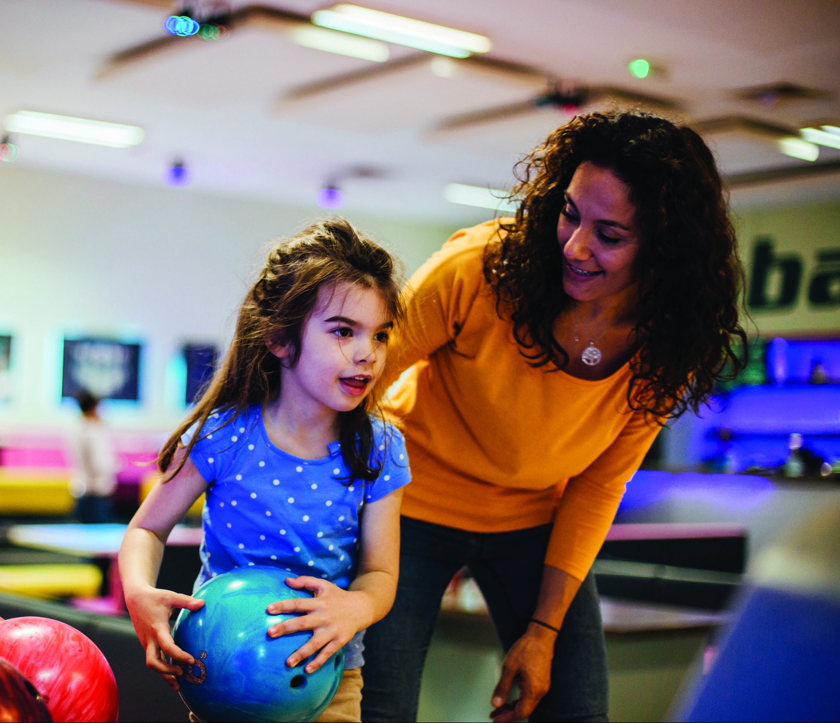 Young smiling woman at the bowling alley with her daughter