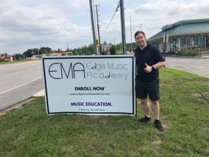 Owner Jason standing next to Edge Music Academy sign near street