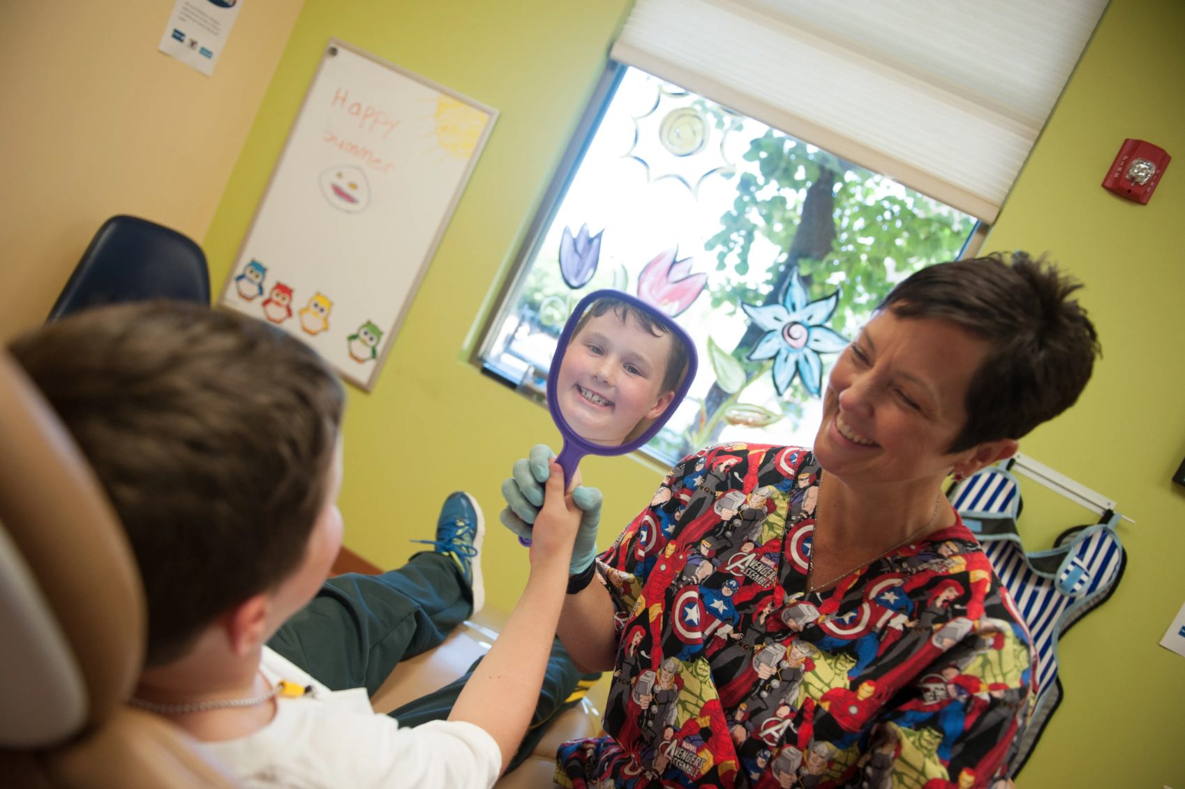 Dentist holding up mirror for child patient - Kids Plus Pediatric Dentistry in Lemont