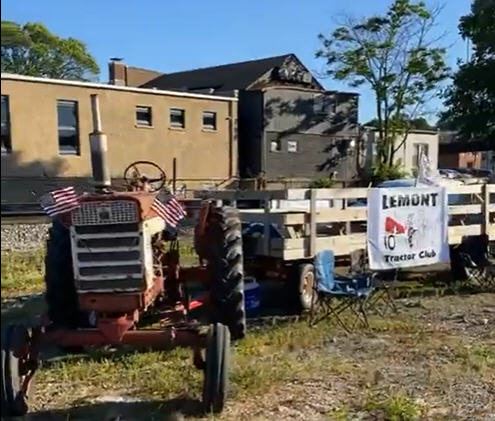 Tractor with small trailer. Trailer has Lemont Tractor Club banner hung from it.