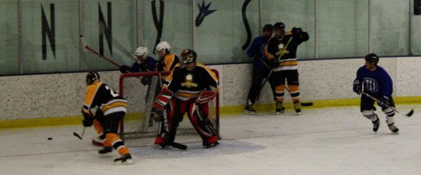 photo from a beer league hockey game, puck going into corner. several players in shot.