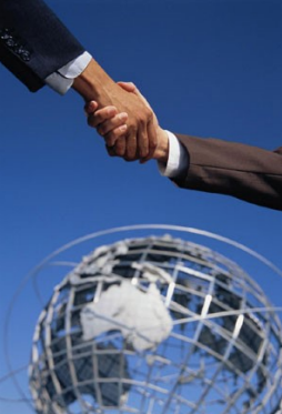 Two hands shaking in front of a globe sculpture