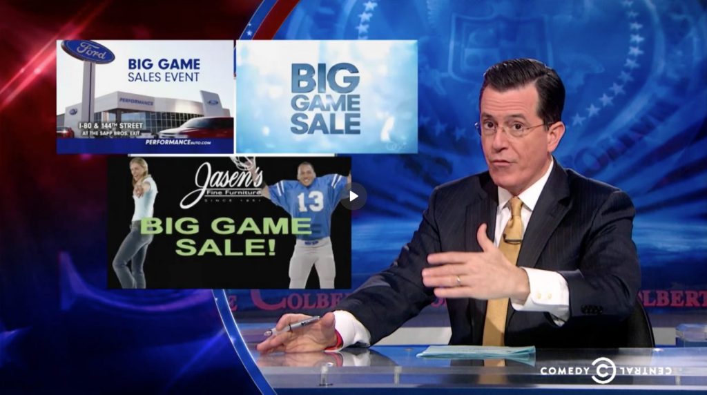 Screen Shot from Episode of Colbert Report, featuring Stephen in front of commercials featuring "Big Game"