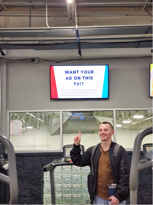 Man pointing at ad screen at Fitness Premier Homer Glen
