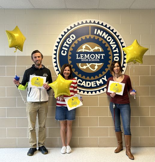 Three Lemont High School faculty standing in front of CITGO Innovation Academy sign holding balloons and certificates